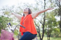 Pretty young girl on bicycle with arms oustretched with joy